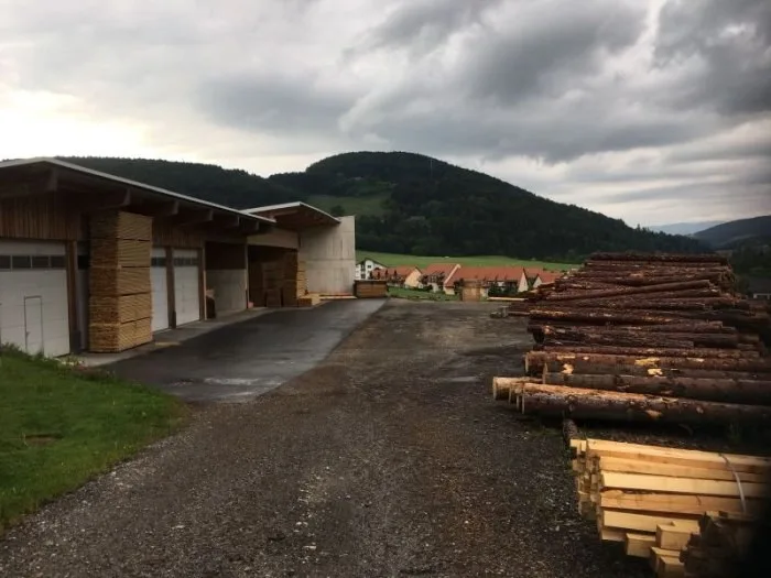 Rundholzplatz mit Holzstämmen und Betriebsgebäude